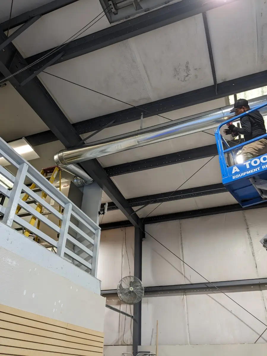 A man in a blue lift is up to the ceiling.