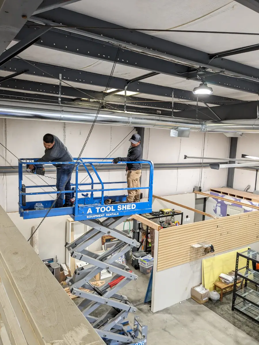 Two men in a scissor lift working on the ceiling.