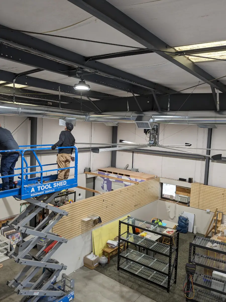 Two men in a scissor lift working on the ceiling.