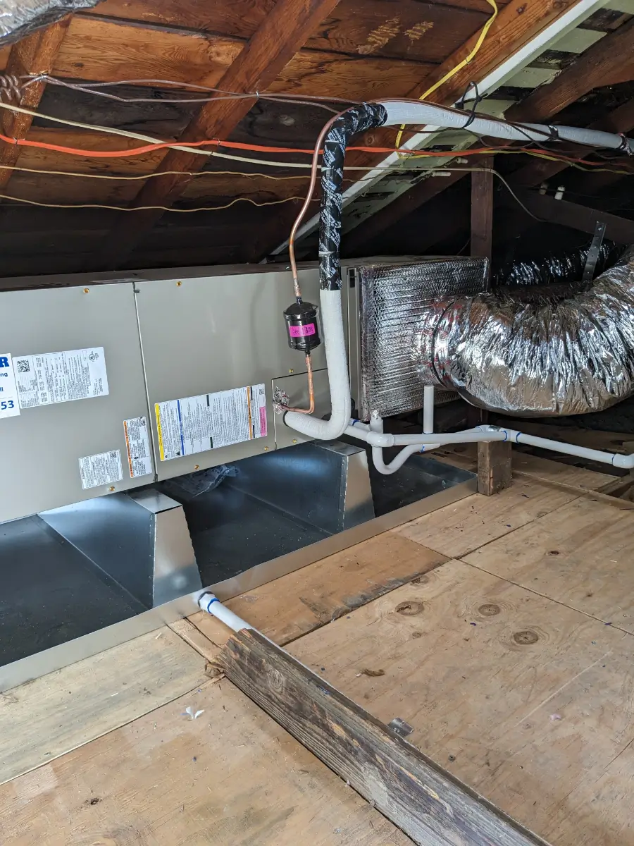 A view of an attic with duct work and air conditioning.