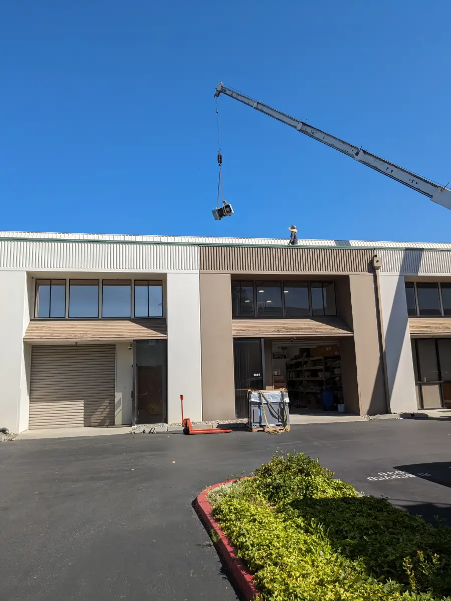 A crane is lifting up the roof of an office building.