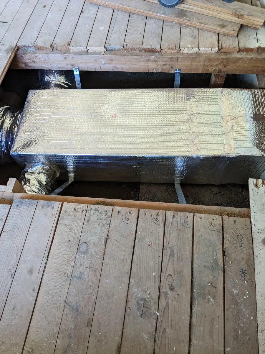 A cat is sitting in the middle of a wooden floor.