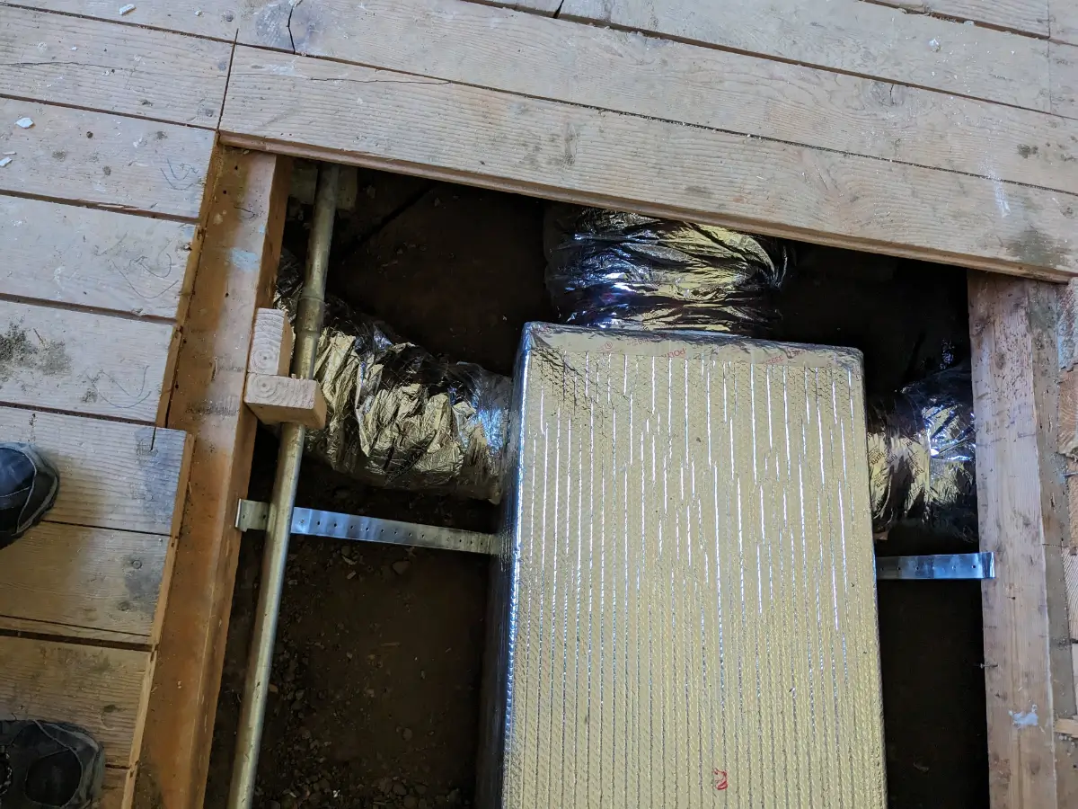 A duct system is installed in the wall of an unfinished building.